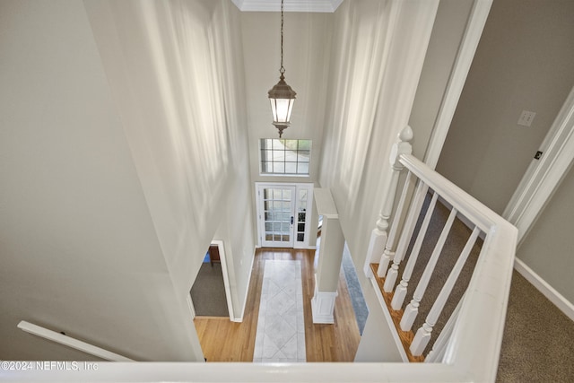 stairs with wood-type flooring and crown molding