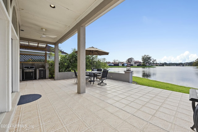 view of patio / terrace with area for grilling, ceiling fan, a water view, and grilling area