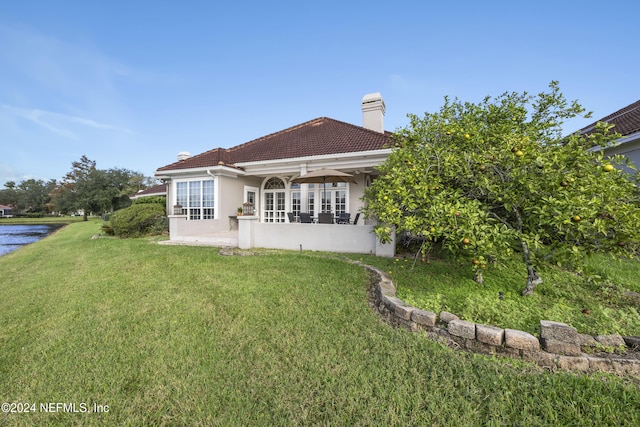 back of property featuring a lawn and a water view