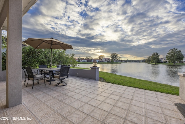 patio terrace at dusk with a lawn and a water view