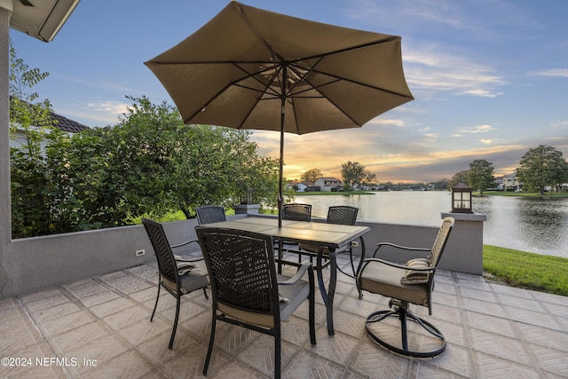 patio terrace at dusk featuring a water view