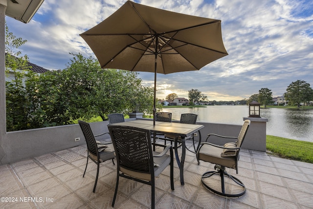 patio terrace at dusk featuring a water view