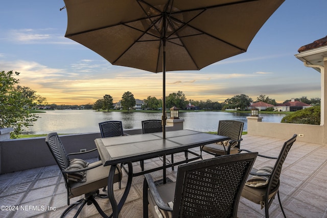 patio terrace at dusk featuring a water view