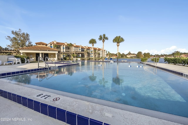 view of pool with a water view and a patio