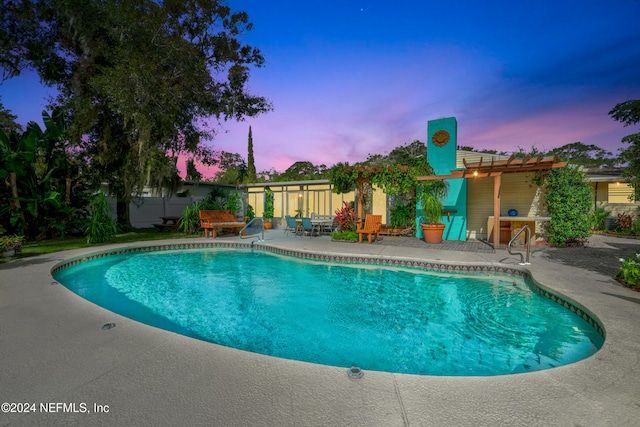 pool at dusk featuring a patio area and a pergola