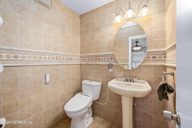 bathroom featuring ceiling fan, tile patterned flooring, tile walls, and toilet