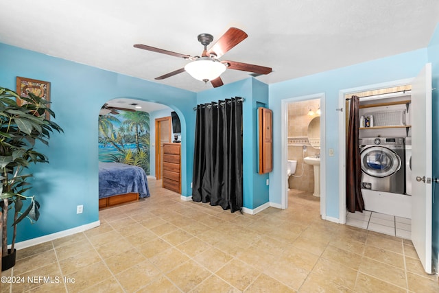 bedroom with ceiling fan, independent washer and dryer, light tile patterned floors, and ensuite bath