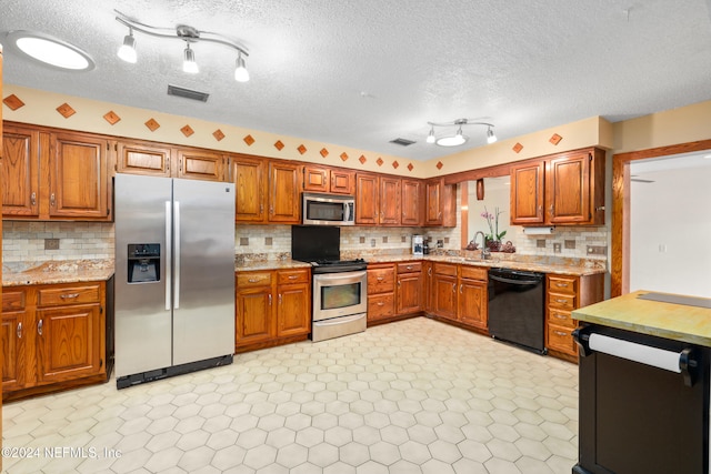 kitchen with decorative backsplash, a textured ceiling, stainless steel appliances, and sink