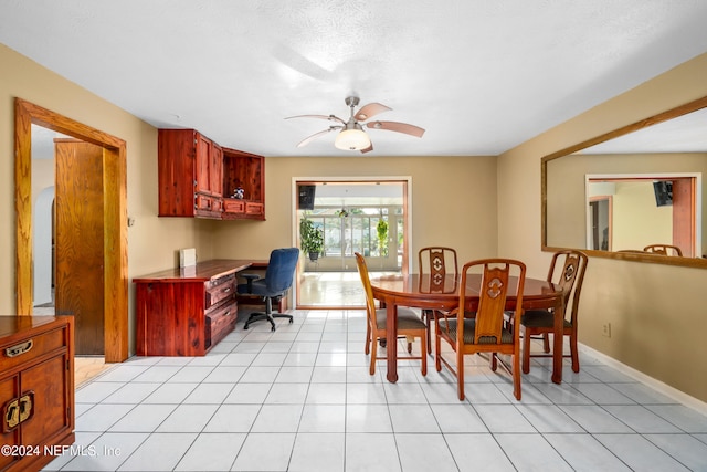 dining space featuring ceiling fan, light tile patterned flooring, and a textured ceiling