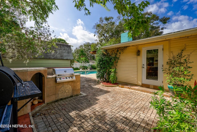 view of patio with an outdoor kitchen, area for grilling, and a fenced in pool