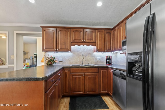 kitchen with kitchen peninsula, light wood-type flooring, stainless steel appliances, crown molding, and sink