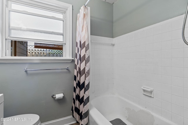 bathroom featuring shower / bath combination with curtain and toilet