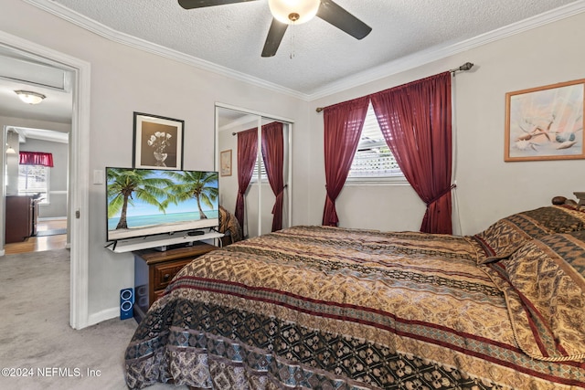 carpeted bedroom with ceiling fan, a closet, crown molding, and a textured ceiling