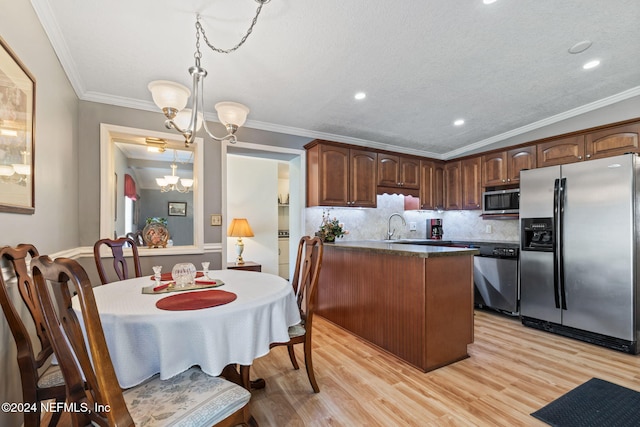 kitchen with ornamental molding, light wood-type flooring, stainless steel appliances, and an inviting chandelier