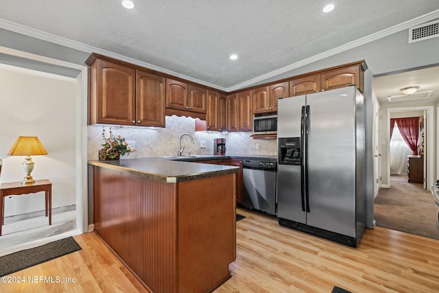 kitchen featuring appliances with stainless steel finishes, light hardwood / wood-style floors, vaulted ceiling, and crown molding