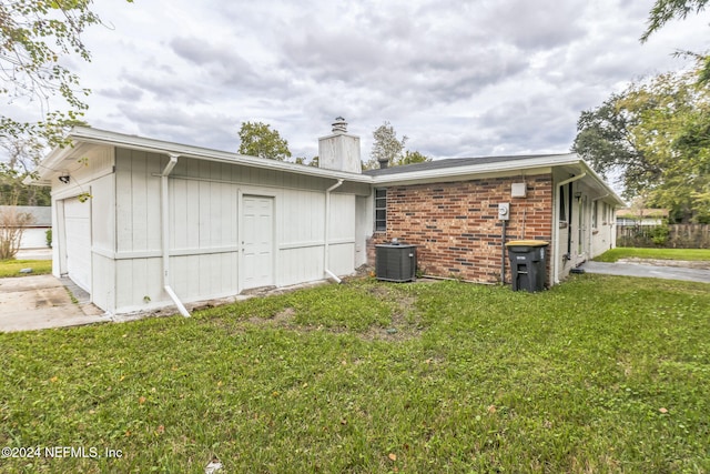 view of property exterior with a lawn, a garage, and central air condition unit