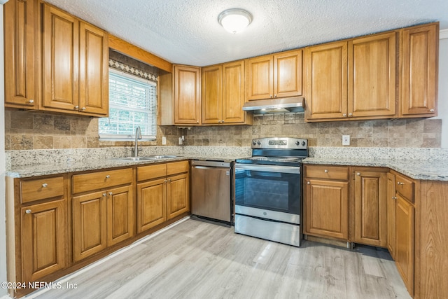 kitchen with sink, light hardwood / wood-style flooring, light stone countertops, a textured ceiling, and stainless steel appliances