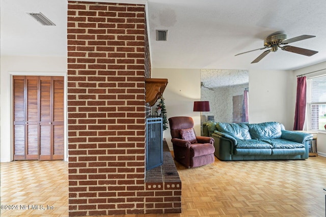 living room featuring ceiling fan, a textured ceiling, and parquet floors