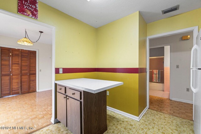 kitchen featuring light parquet flooring, a textured ceiling, and white fridge