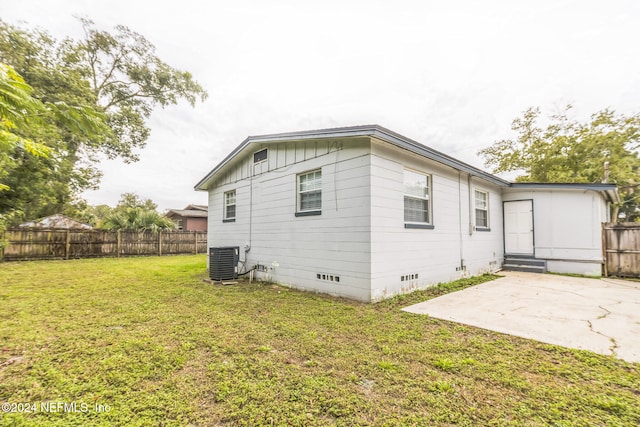 view of side of home with a yard, a patio, and central AC unit