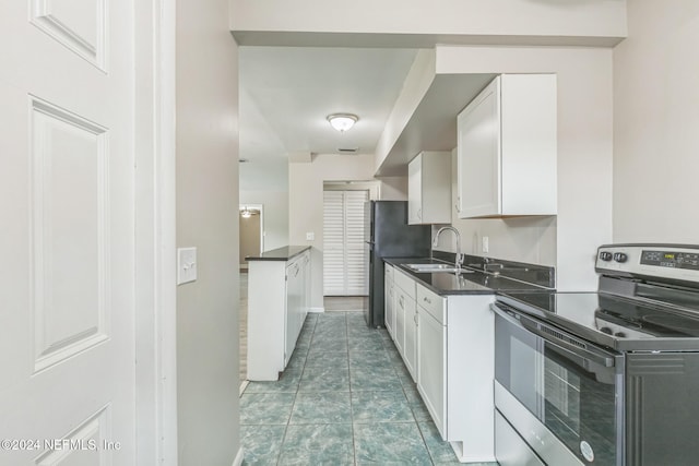 kitchen featuring refrigerator, stainless steel range with electric stovetop, sink, white cabinets, and tile patterned flooring