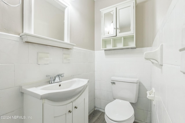 bathroom with hardwood / wood-style flooring, vanity, toilet, and tile walls