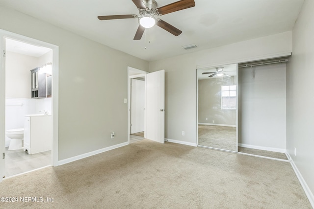 unfurnished bedroom featuring light carpet, sink, ceiling fan, connected bathroom, and a closet