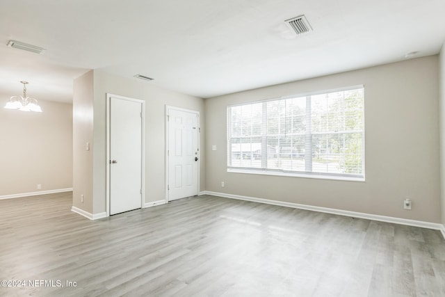 unfurnished room with light wood-type flooring and an inviting chandelier