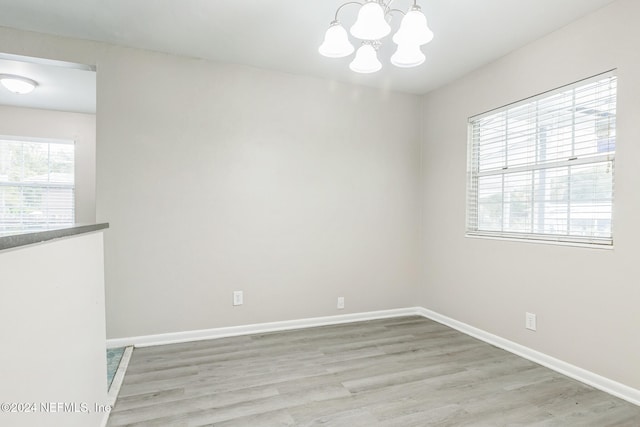 empty room featuring light hardwood / wood-style floors and a notable chandelier