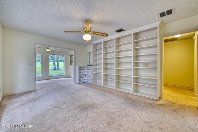 unfurnished living room with ceiling fan, carpet, and a textured ceiling