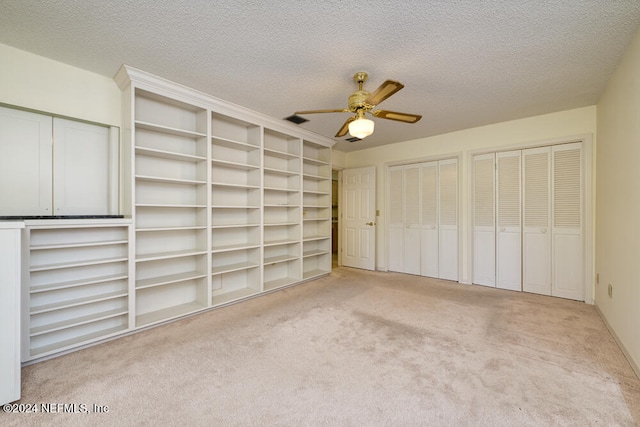 unfurnished bedroom with ceiling fan, light colored carpet, and a textured ceiling