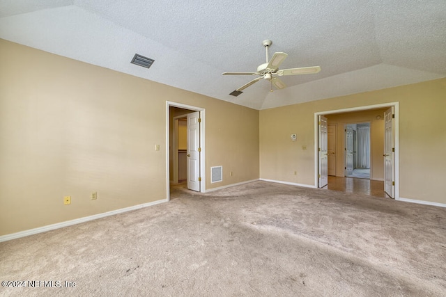 spare room featuring light carpet, a textured ceiling, vaulted ceiling, and ceiling fan