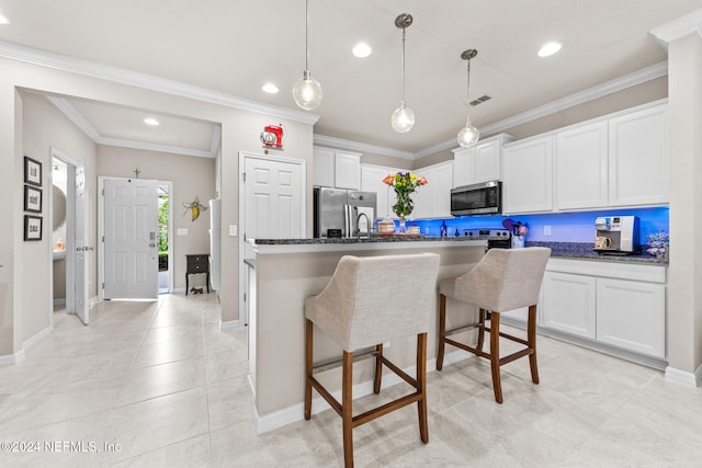 kitchen featuring a center island with sink, crown molding, dark stone counters, stainless steel appliances, and white cabinets