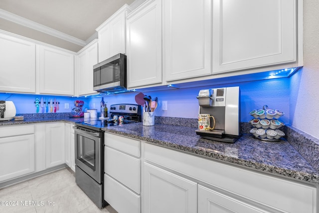 kitchen featuring stainless steel appliances, light tile patterned flooring, ornamental molding, dark stone counters, and white cabinets