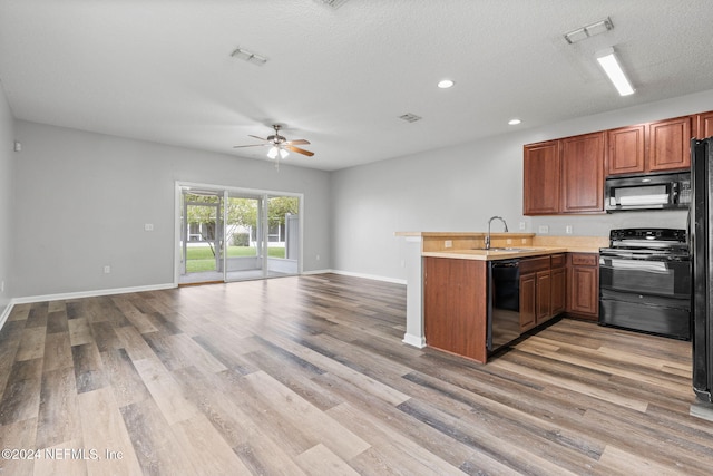 kitchen with sink, black appliances, kitchen peninsula, ceiling fan, and light hardwood / wood-style flooring