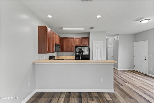 kitchen with kitchen peninsula, light hardwood / wood-style floors, black appliances, and a textured ceiling