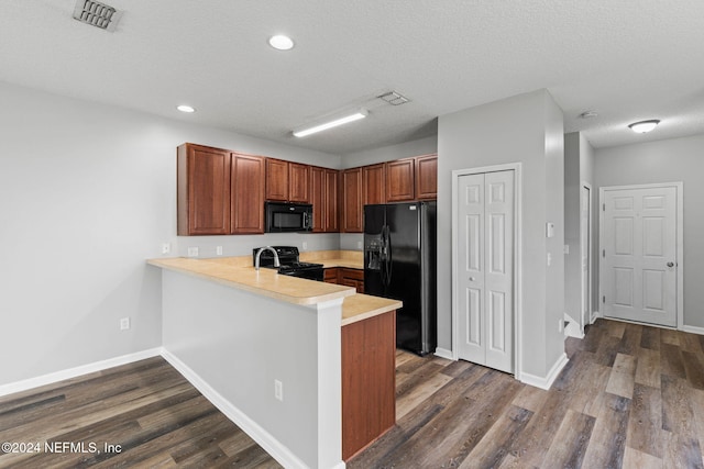 kitchen featuring dark wood-type flooring, a textured ceiling, black appliances, and kitchen peninsula