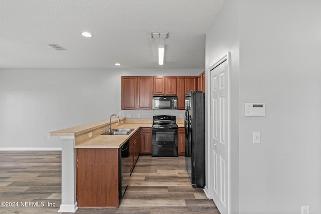 kitchen featuring kitchen peninsula, black appliances, hardwood / wood-style flooring, and sink