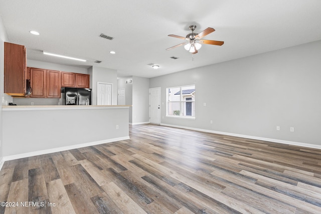 unfurnished living room with a textured ceiling, hardwood / wood-style flooring, and ceiling fan