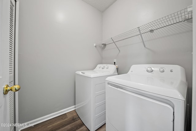 laundry area featuring a textured ceiling, washer and clothes dryer, and dark hardwood / wood-style floors