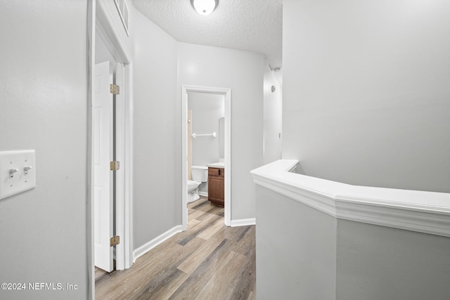 corridor with wood-type flooring and a textured ceiling