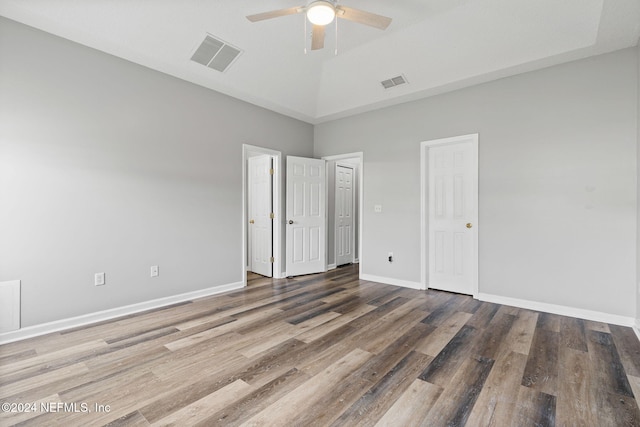 unfurnished bedroom with a towering ceiling, ceiling fan, and dark hardwood / wood-style floors