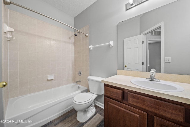 full bathroom featuring a textured ceiling, wood-type flooring, vanity, toilet, and tiled shower / bath combo