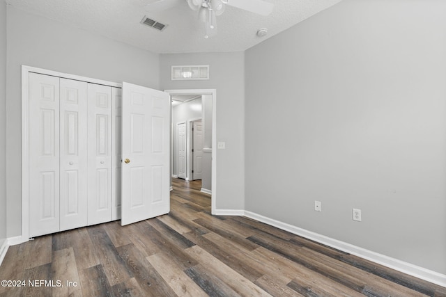 unfurnished bedroom with a textured ceiling, ceiling fan, dark hardwood / wood-style floors, and a closet