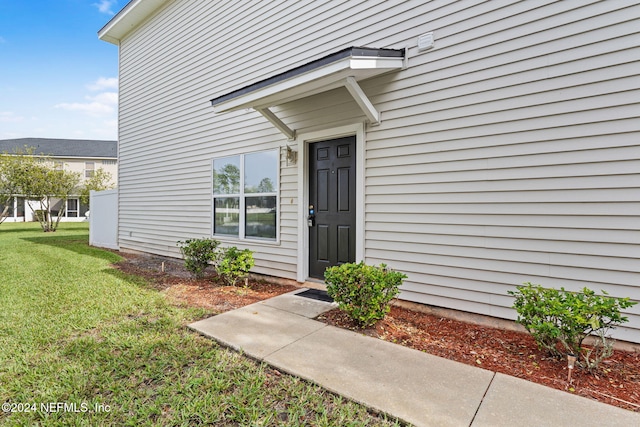 property entrance featuring a lawn