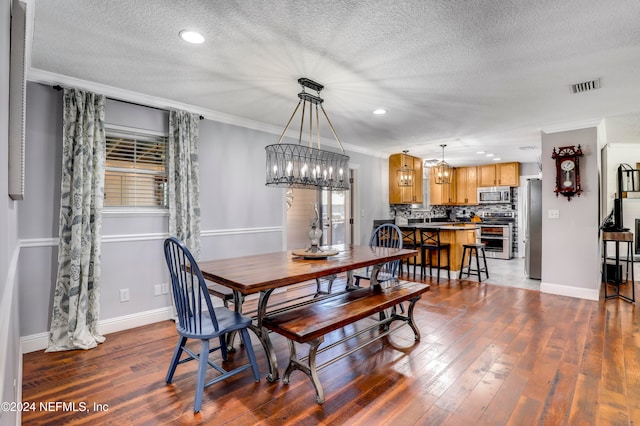 dining room featuring a textured ceiling, dark hardwood / wood-style floors, crown molding, and an inviting chandelier