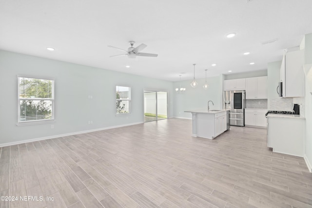 kitchen with white cabinetry, hanging light fixtures, an island with sink, ceiling fan with notable chandelier, and appliances with stainless steel finishes