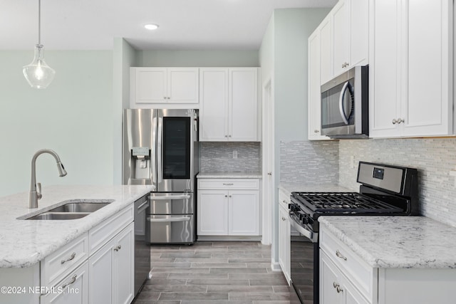 kitchen featuring backsplash, sink, appliances with stainless steel finishes, decorative light fixtures, and white cabinetry