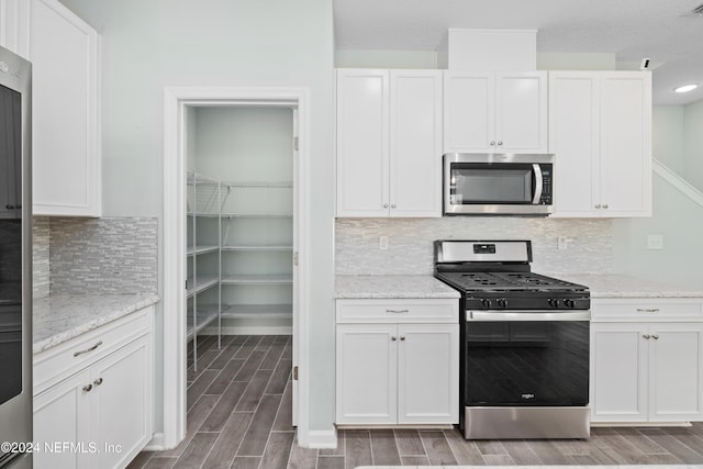 kitchen with light stone countertops, white cabinetry, appliances with stainless steel finishes, and tasteful backsplash