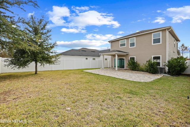 back of property with central AC unit, a patio area, and a yard